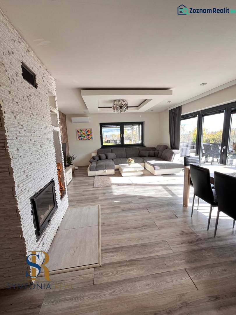 Családi ház belső tere kanapéval, kandallóval és fa dekorációjú padlóval.