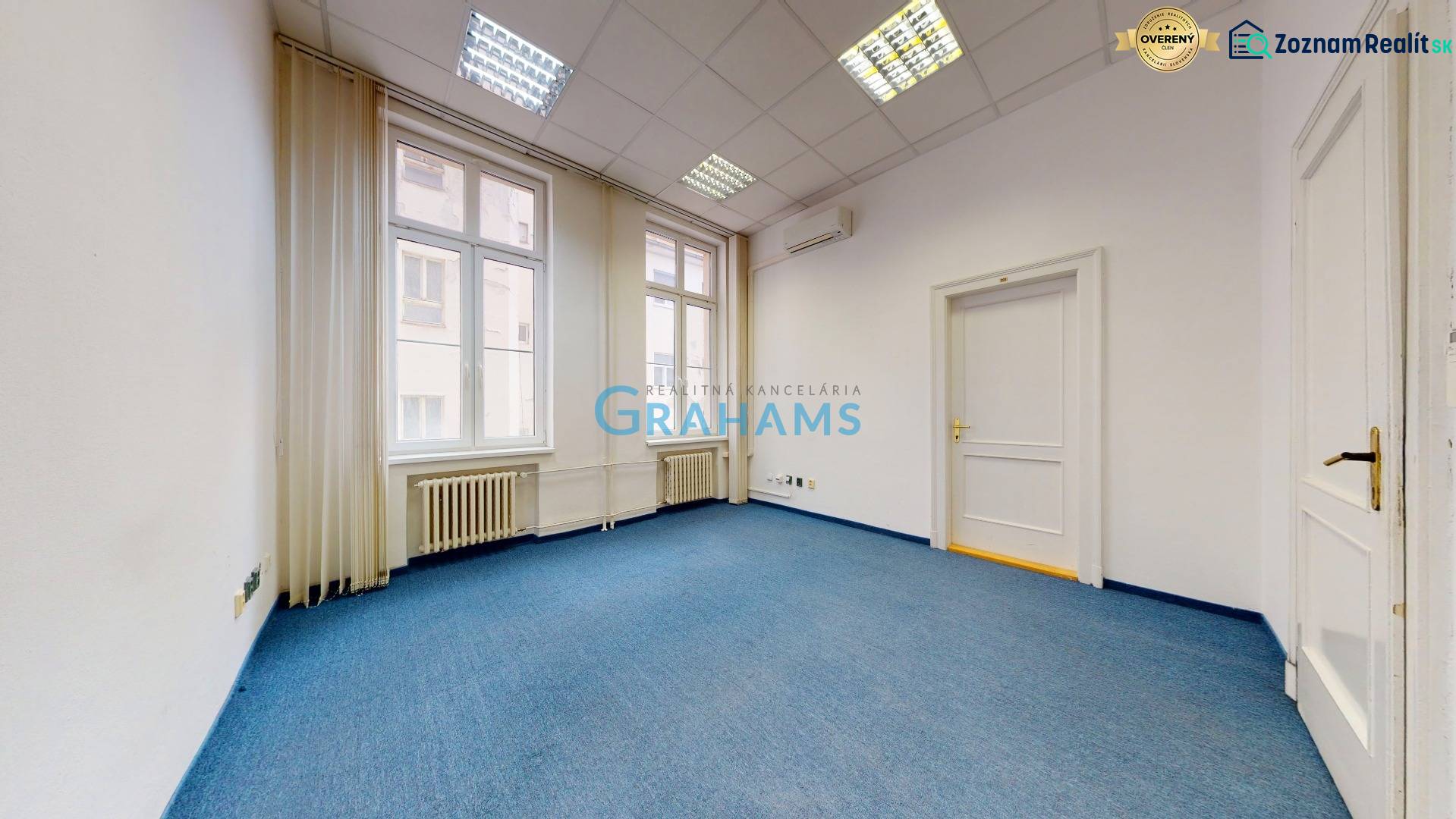 Irodák álmennyezettel, kék szőnyeggel és nagy ablakokkal.
