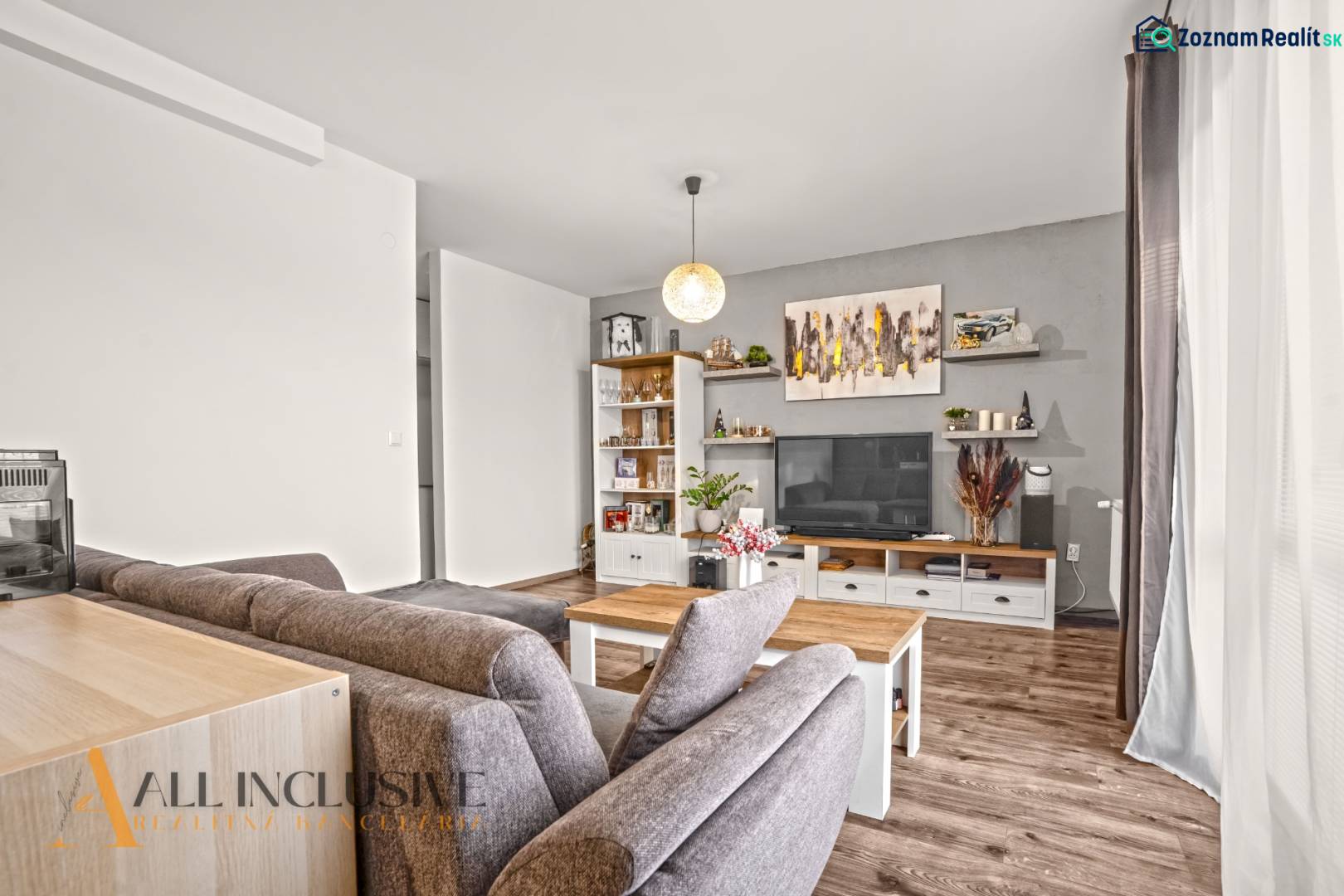 Nappali egy kétszobás lakásban, fa dekoros padlóval, kényelmes ülőgarnitúrával és dekorációkkal.