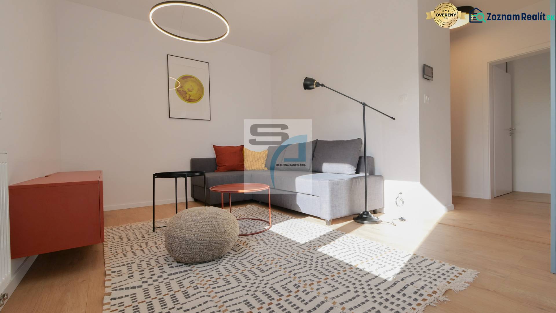 Nappali egy kétszobás lakásban fa dekor padlóval, szürke kanapéval és modern világítással.