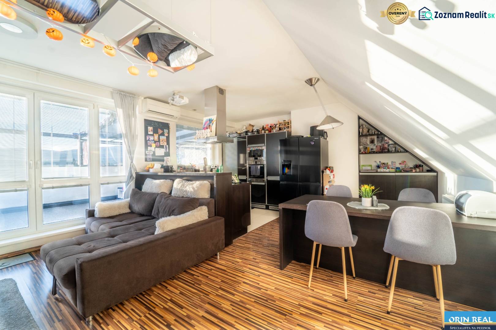 Nappali konyhával egy kétszobás lakásban, fa hatású padlóval és kényelmes kanapéval.