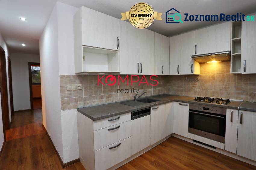 Konyha konyhabútorral és fa dekorációjú padlóval egy háromszobás lakásban.