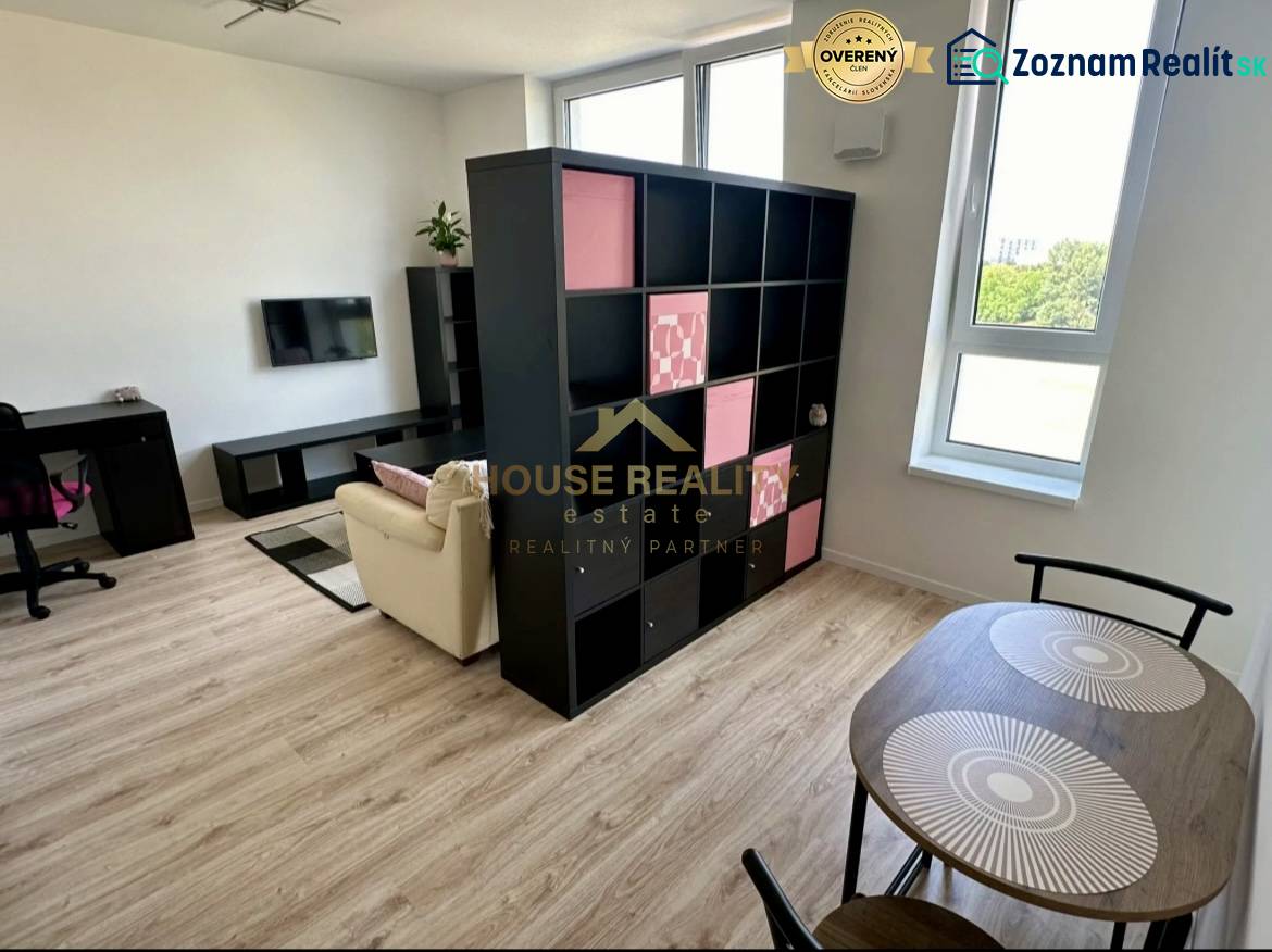 Nappali egy kétszobás lakásban polcos fallal és fa dekoros padlóval.