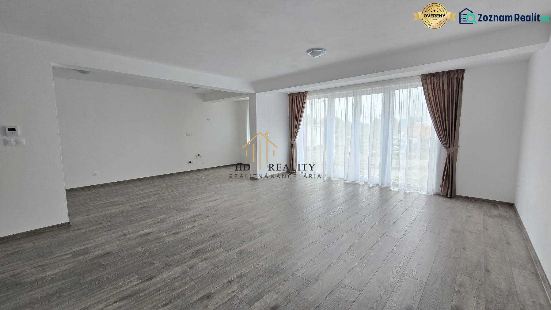 Nappali egy családi házban padlóval és világos falakkal, nagy ablakokkal.