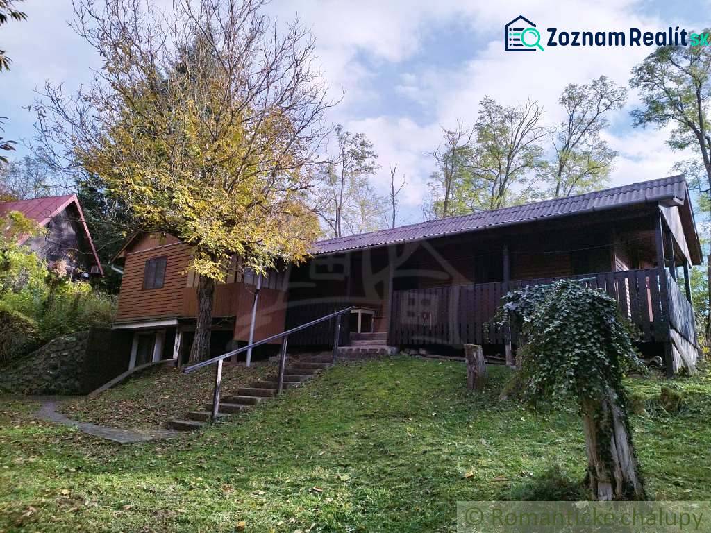 Házikó Dudincon, természet által körülvéve, terasszal és fákkal az udvaron.