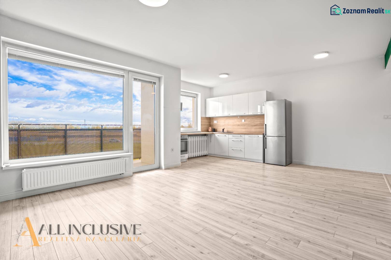 Világos belső tér kétszobás lakásban konyhával, üvegfallal és fa dekorációjú padlóval.