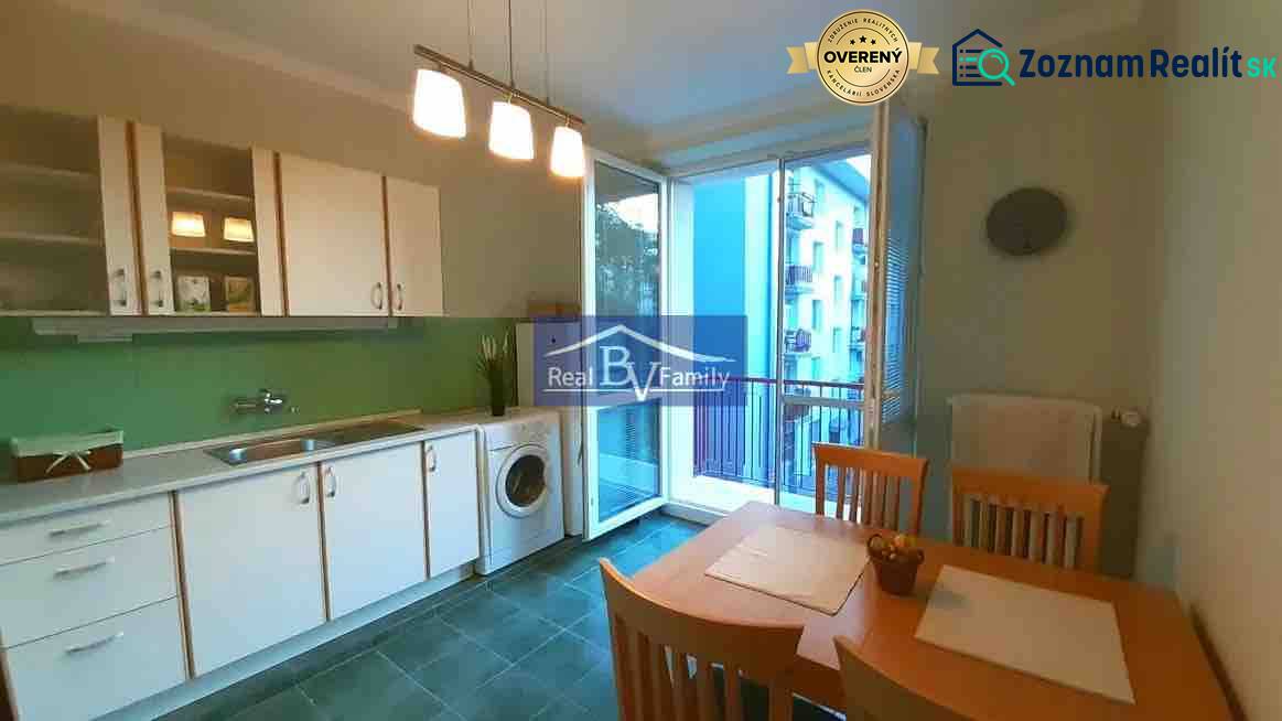 Konyha egy kétszobás lakásban fehér szekrényekkel, étkezőasztallal és erkéllyel.