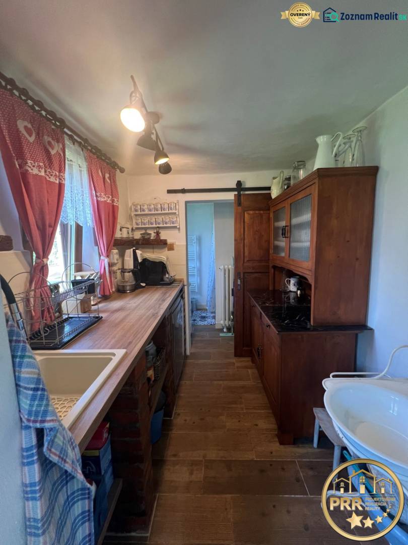 Konyha egy faházban rusztikus bútorokkal, mosogatóval és dekoratív függönyökkel.