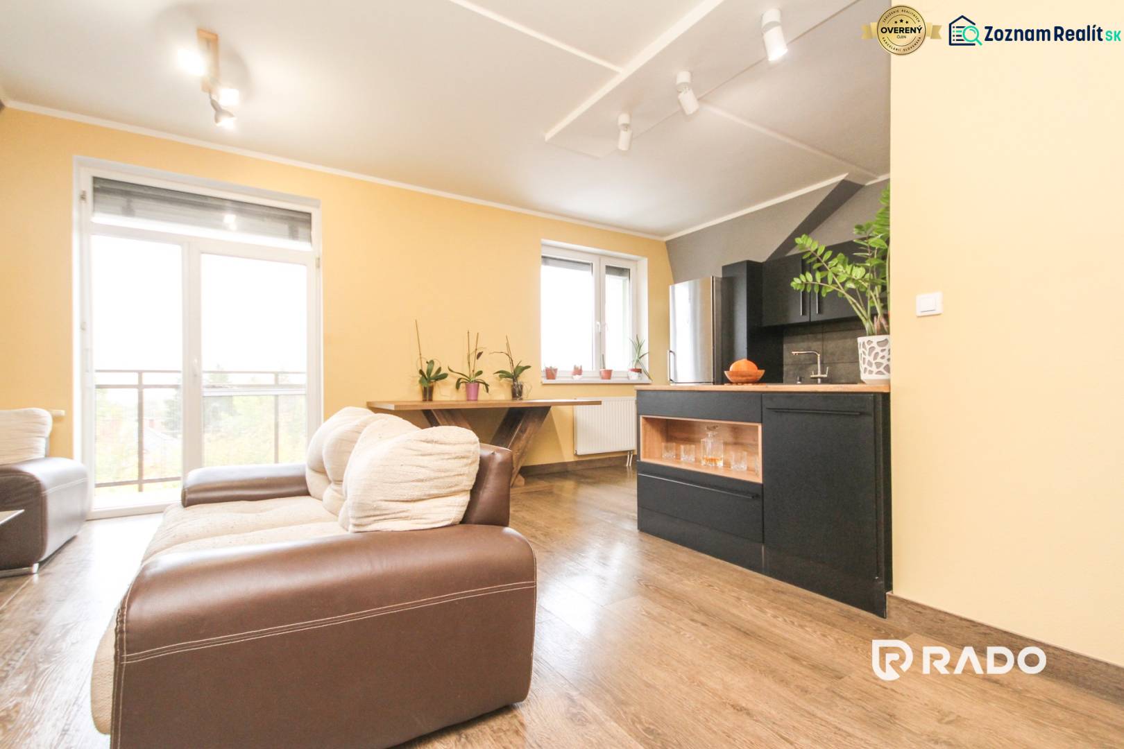 Nappali egy négy szobás lakásban, fa mintázatú padlóval és kanapéval.