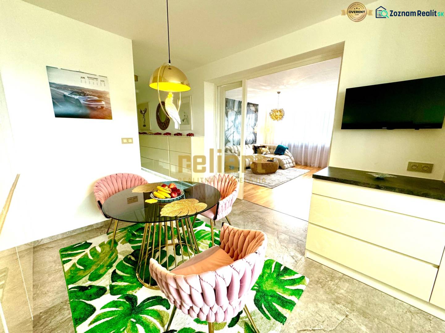 Étkező sarok kerek asztallal, székekkel és televízióval egy háromszobás lakásban.