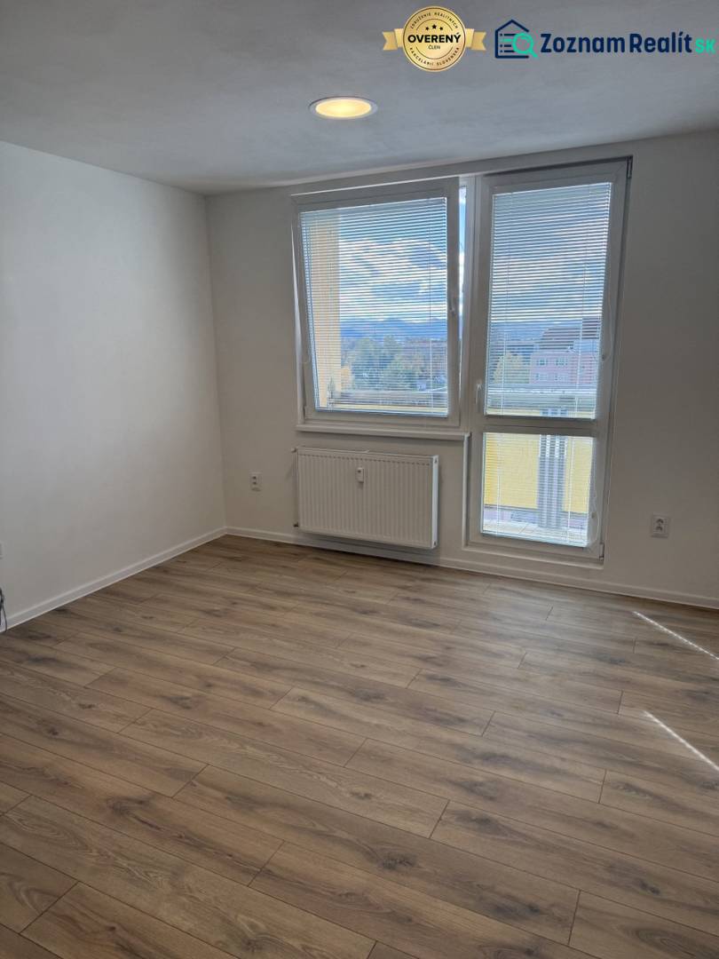 Garzonlakás fa dekor padlóval és nagy ablakkal, amely kilátást nyújt a környékre.