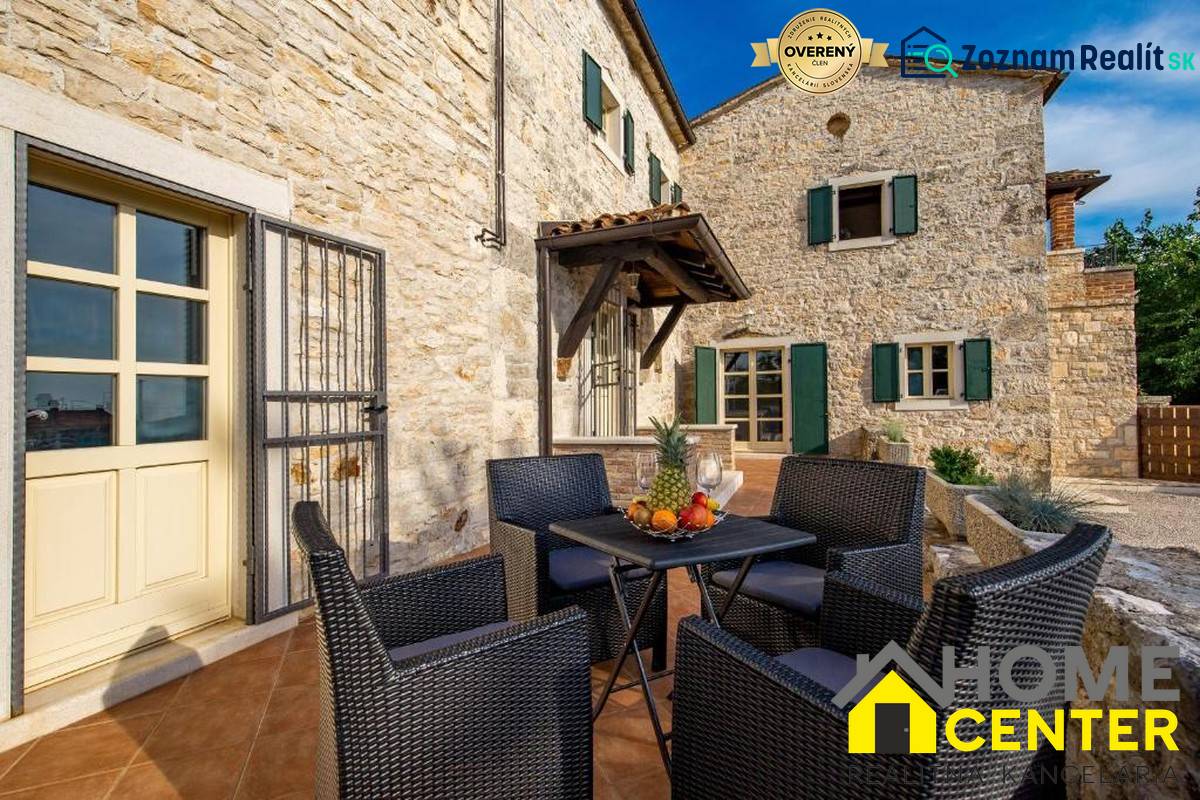 Egy villa kő homlokzata Baléban, kinti ülőgarnitúrával és gyümölcsökkel az asztalon.