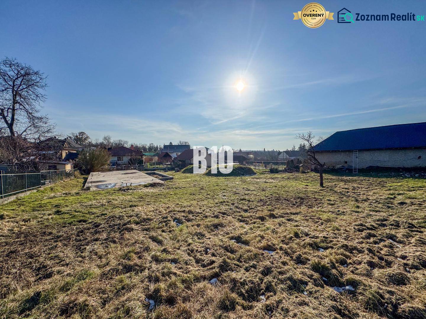 Telek betonalappal készen áll a lakhatásra, napos időjárás és környező táj.