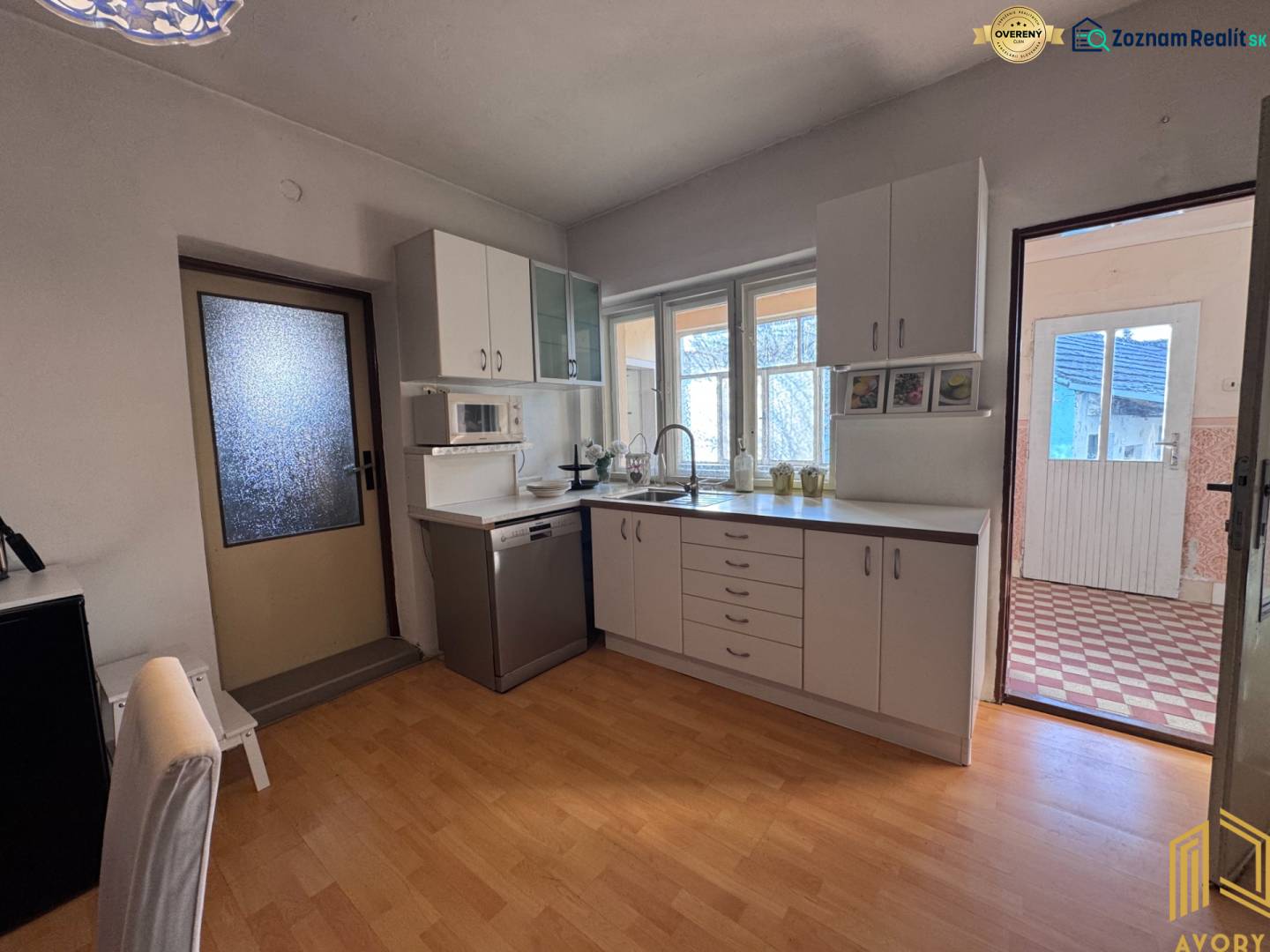 Konyha fehér konyhaszekrénnyel és fa dekorációjú padlóval egy családi házban.