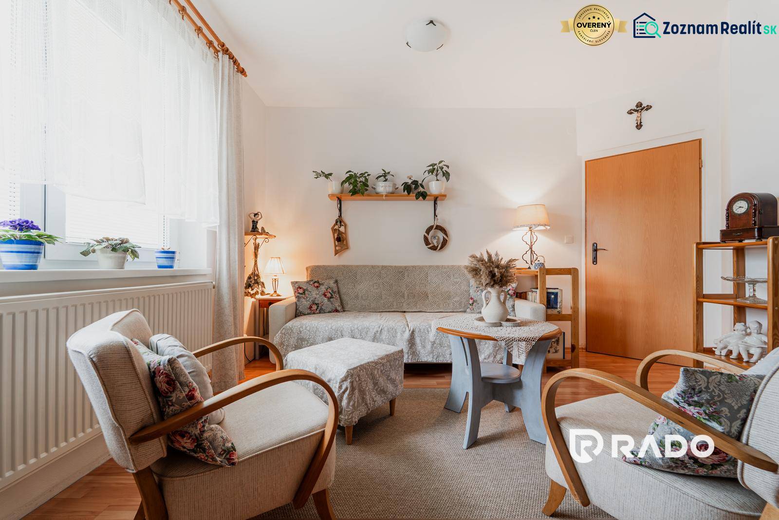 Nappali dekorációkkal, fa mintázatú padlóval és kényelmes ülőgarnitúrával egy háromszobás lakásban.