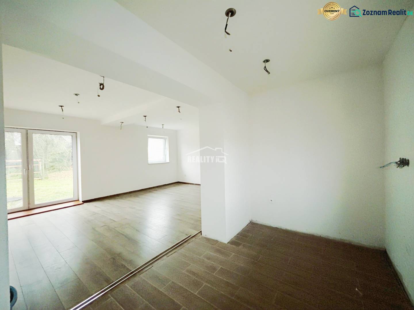 Családi ház belső tere fa dekorációjú padlóval és nagy ablakokkal a kertre.