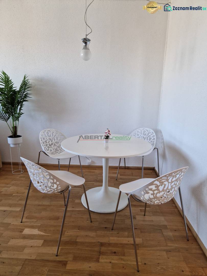 Étkező sarok egy háromszobás lakásban, fa dekorációjú padlóval és díszes székekkel.