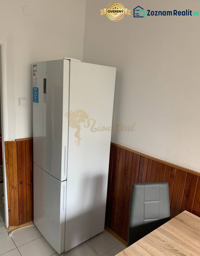 Konyha egy kétszobás lakásban hűtőszekrénnyel, sötét burkolattal és étkezősarokkal.