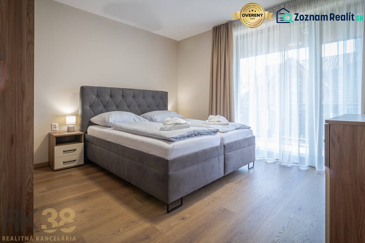 Hálószoba egy kétszobás lakásban nagy ággyal és fa mintázatú padlóval.