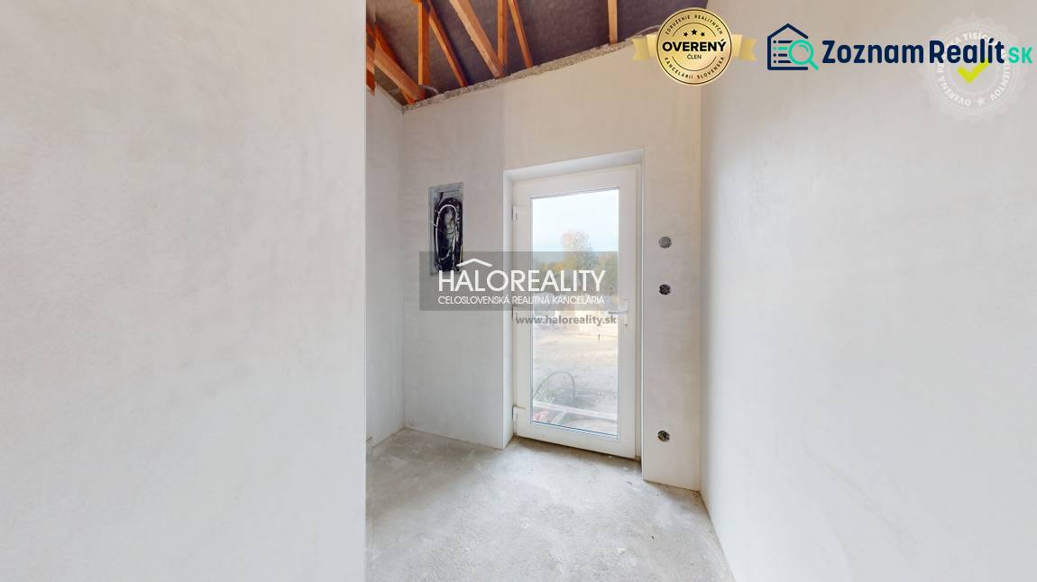 Világos szoba egy családi házban betonpadlóval és üvegajtókkal.