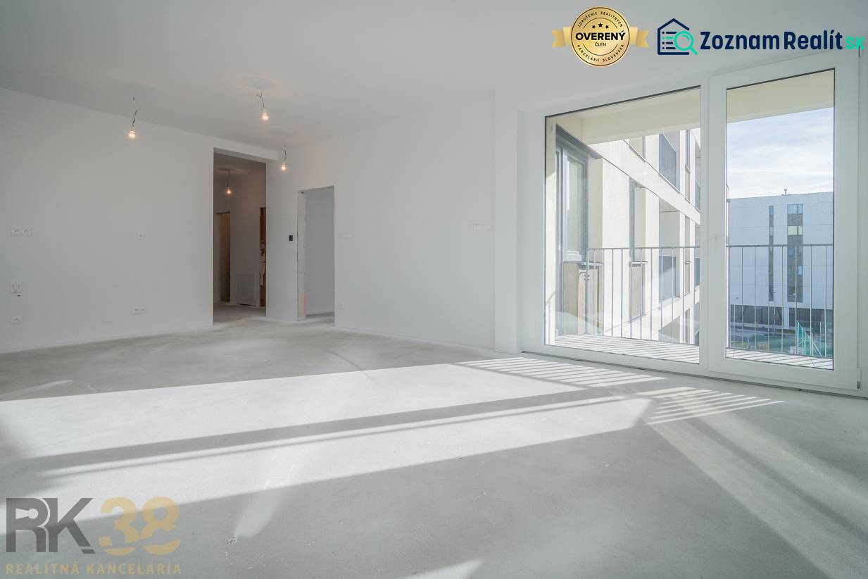 Szoba egy háromszobás lakásban nagy ablakkal, fa dekorációjú padlóval, fehér falakkal.