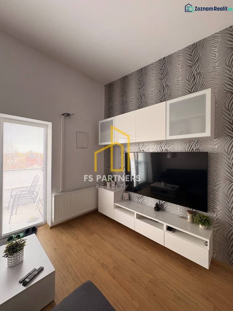 Nappali TV-fallal, mintás tapétával és fa dekoros padlóval egy kétszobás lakásban.