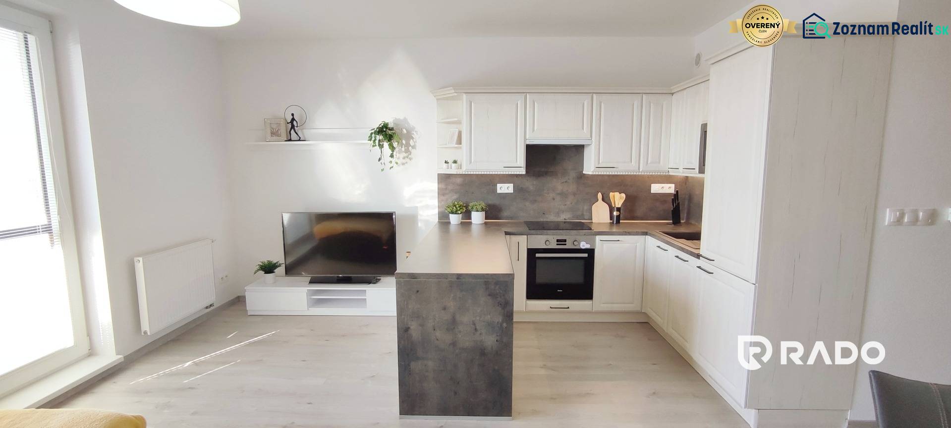 Nappali konyhasarokkal, világos padló fa dekorral egy kétszobás lakásban.