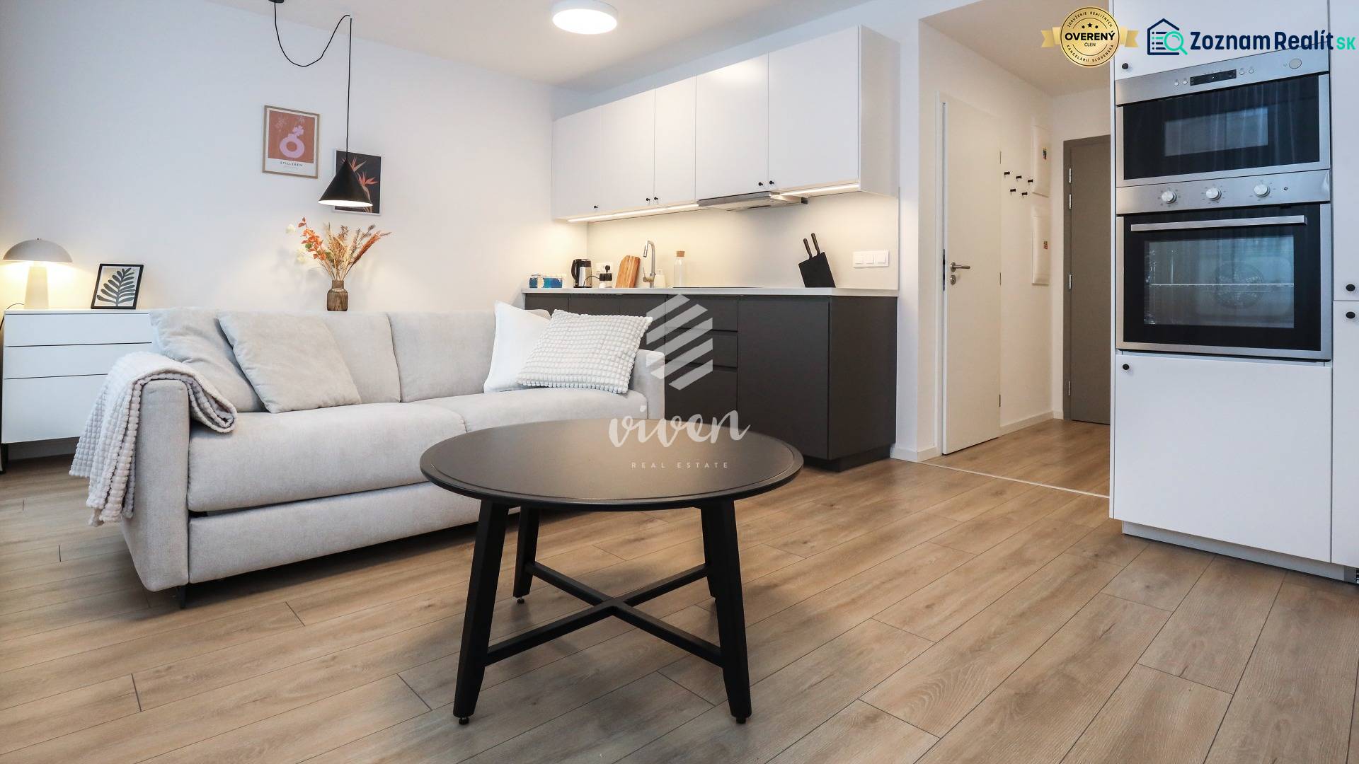 Nappali konyhasarokkal egy szobás lakásban, fa dekorációjú padlóval.