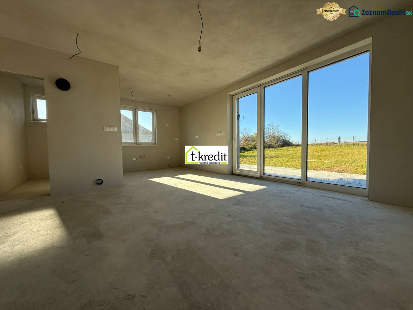 Tágas családi ház belső tér nagy ablakokkal és kilátással a kertre.