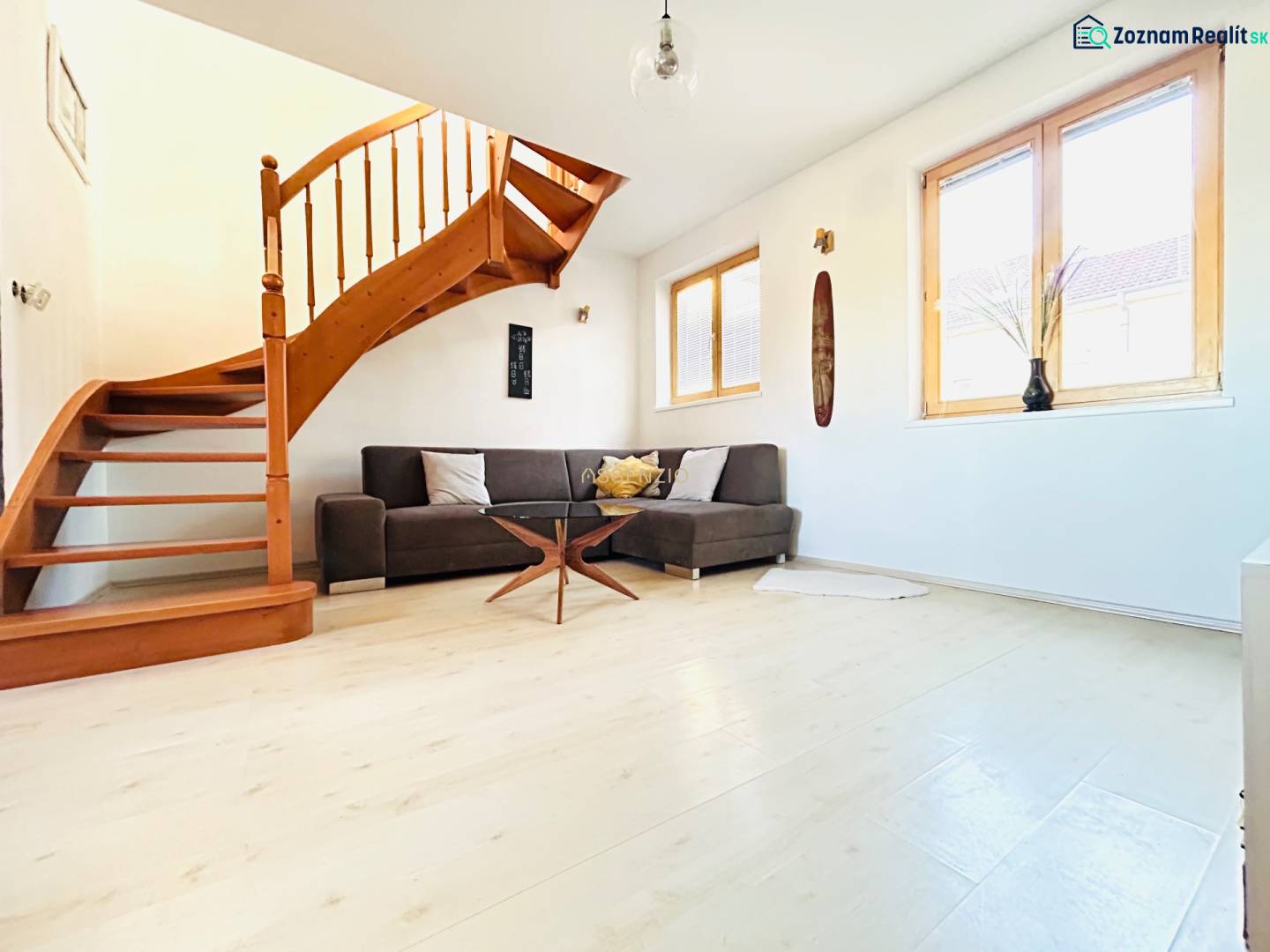 Nappali egy kétszobás lakásban csigalépcsővel és fa dekoros padlóval.