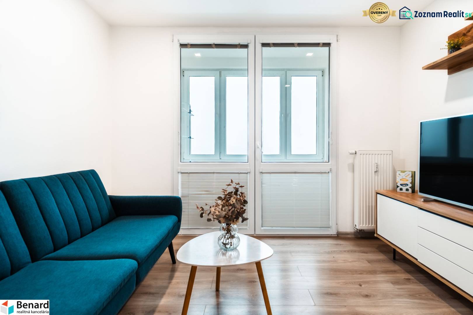 Nappali egy kétszobás lakásban kanapéval, televízióval és fa dekorációjú padlóval.