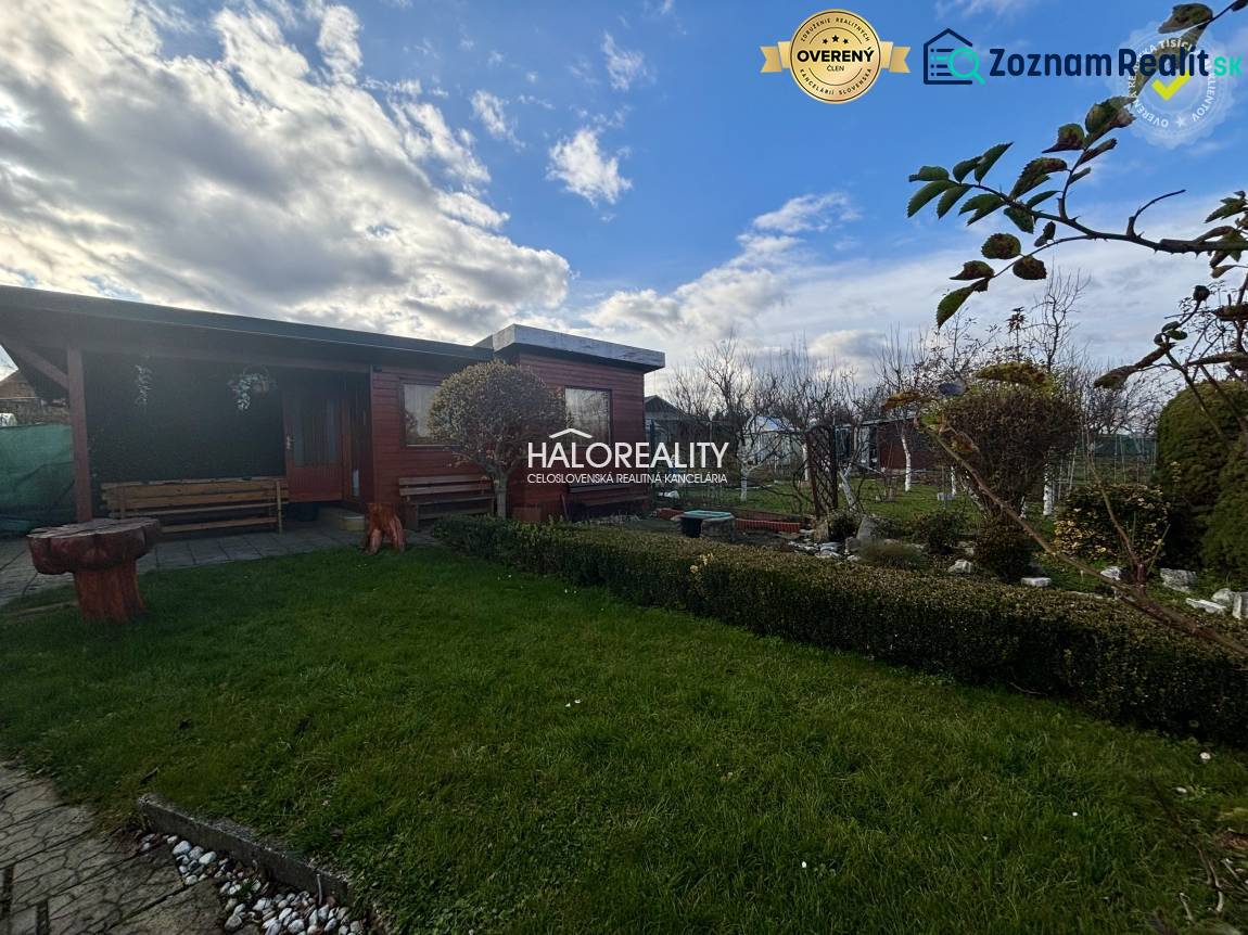 Fából készült pavilon a kertben Iglón, zöld gyep és növényzet mellett.