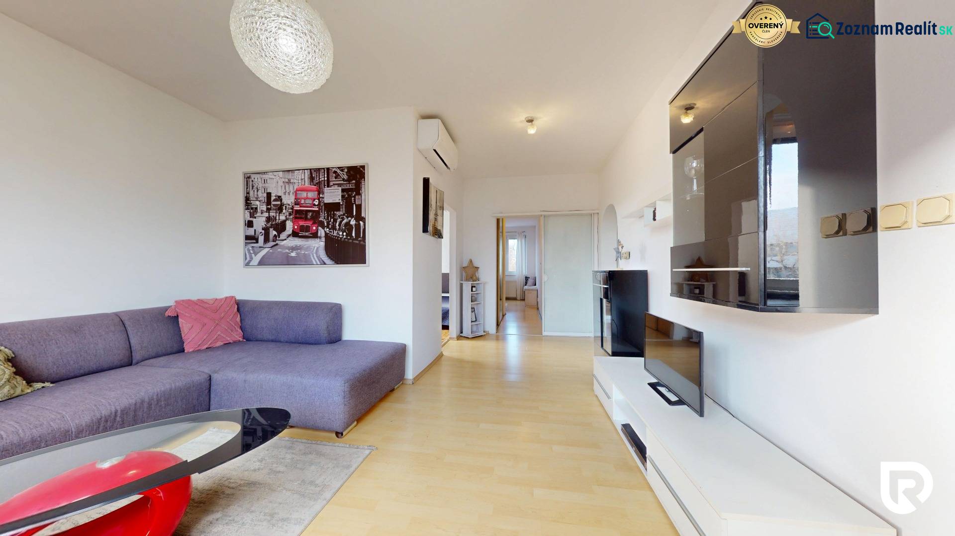 Nappali egy háromszobás lakásban kanapéval, TV egységgel és fa dekorációjú padlóval.