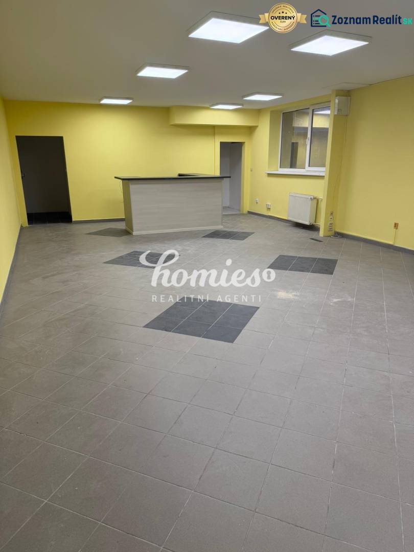 Sárga falak, szürke padló és fa pult az üzlethelyiségben.