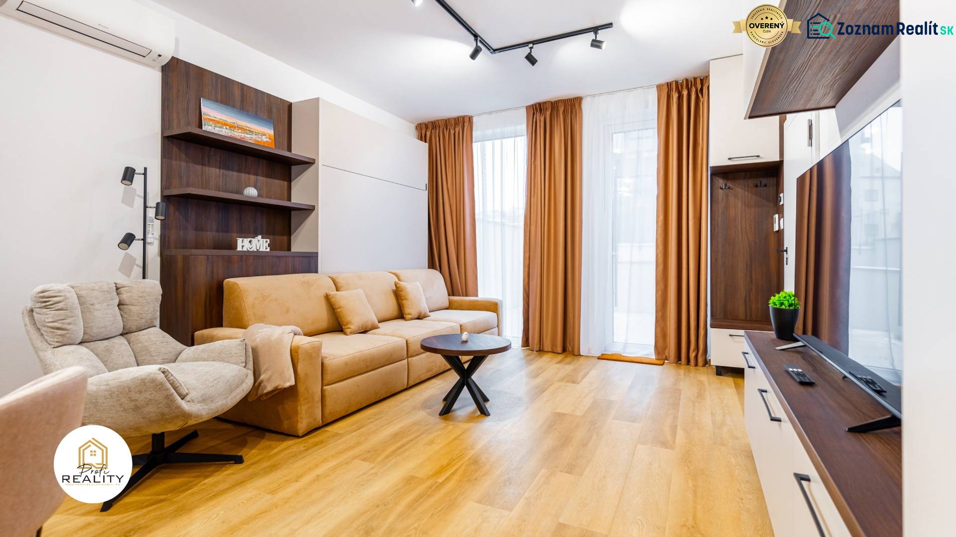 Nappali kanapéval, fotellel és fa mintázatú padlóval egy egyszobás lakásban.