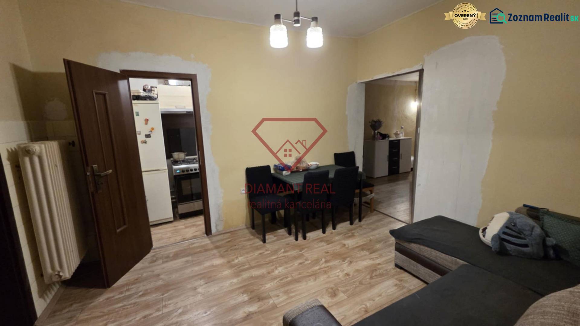 Nappali egy családi házban, fa mintázatú padlóval, asztallal és kanapéval.