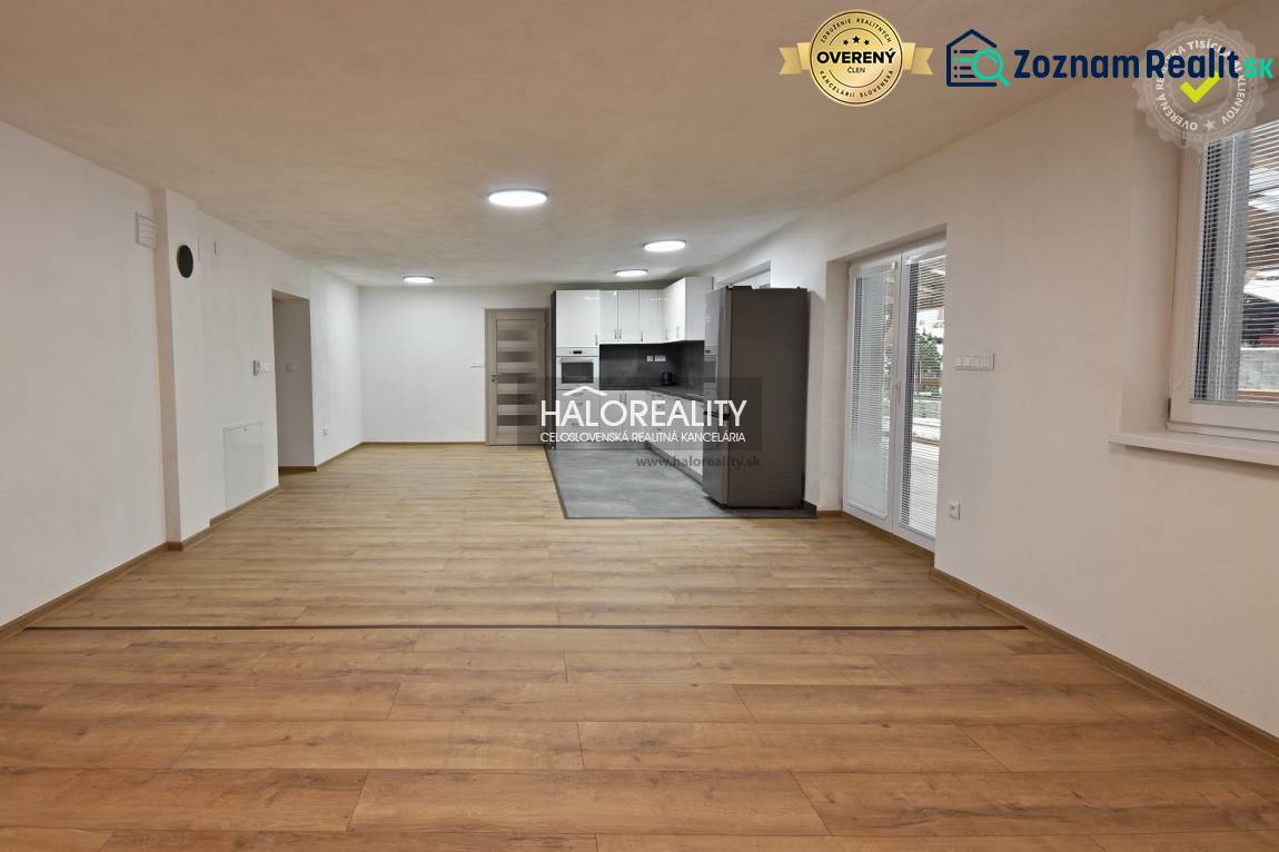 Nappali családi házban konyhával, fa mintás padló, fehér falak.