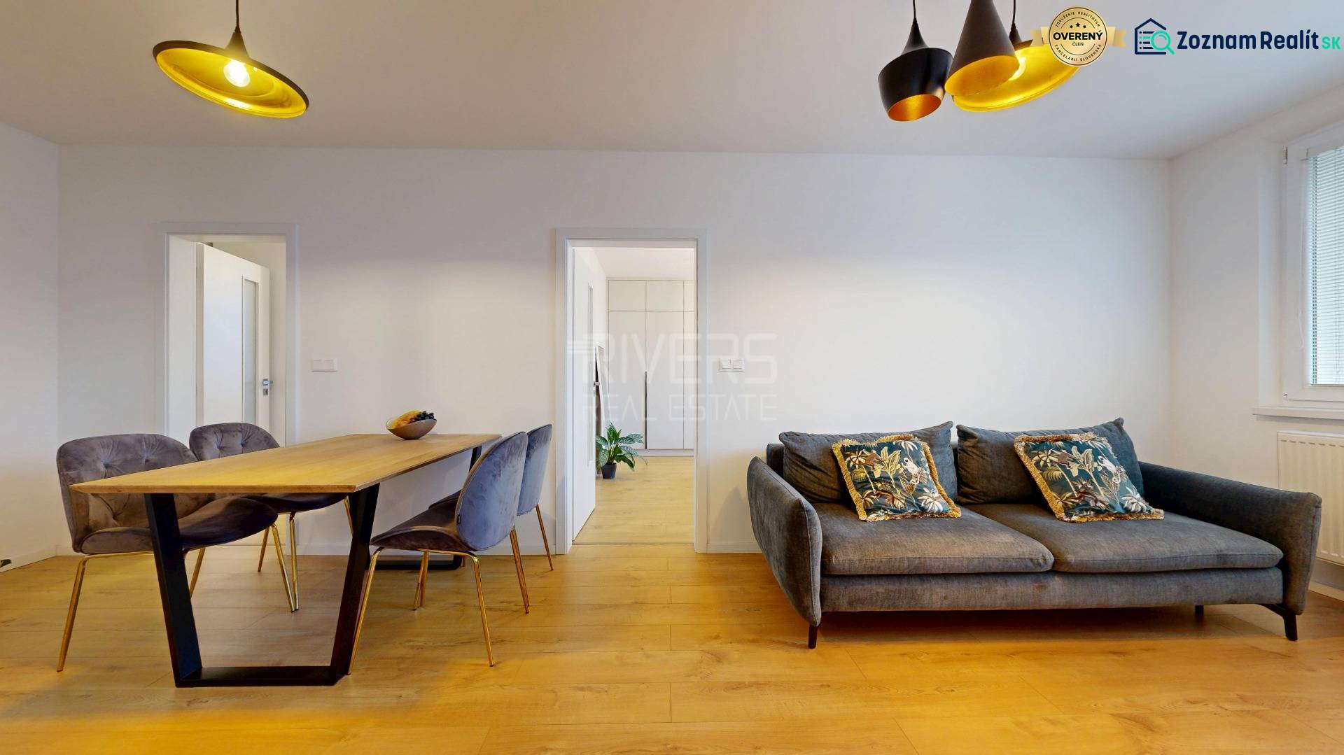 Nappali egy háromszobás lakásban szalonnal, étkezőasztallal és fa dekorációjú padlóval.