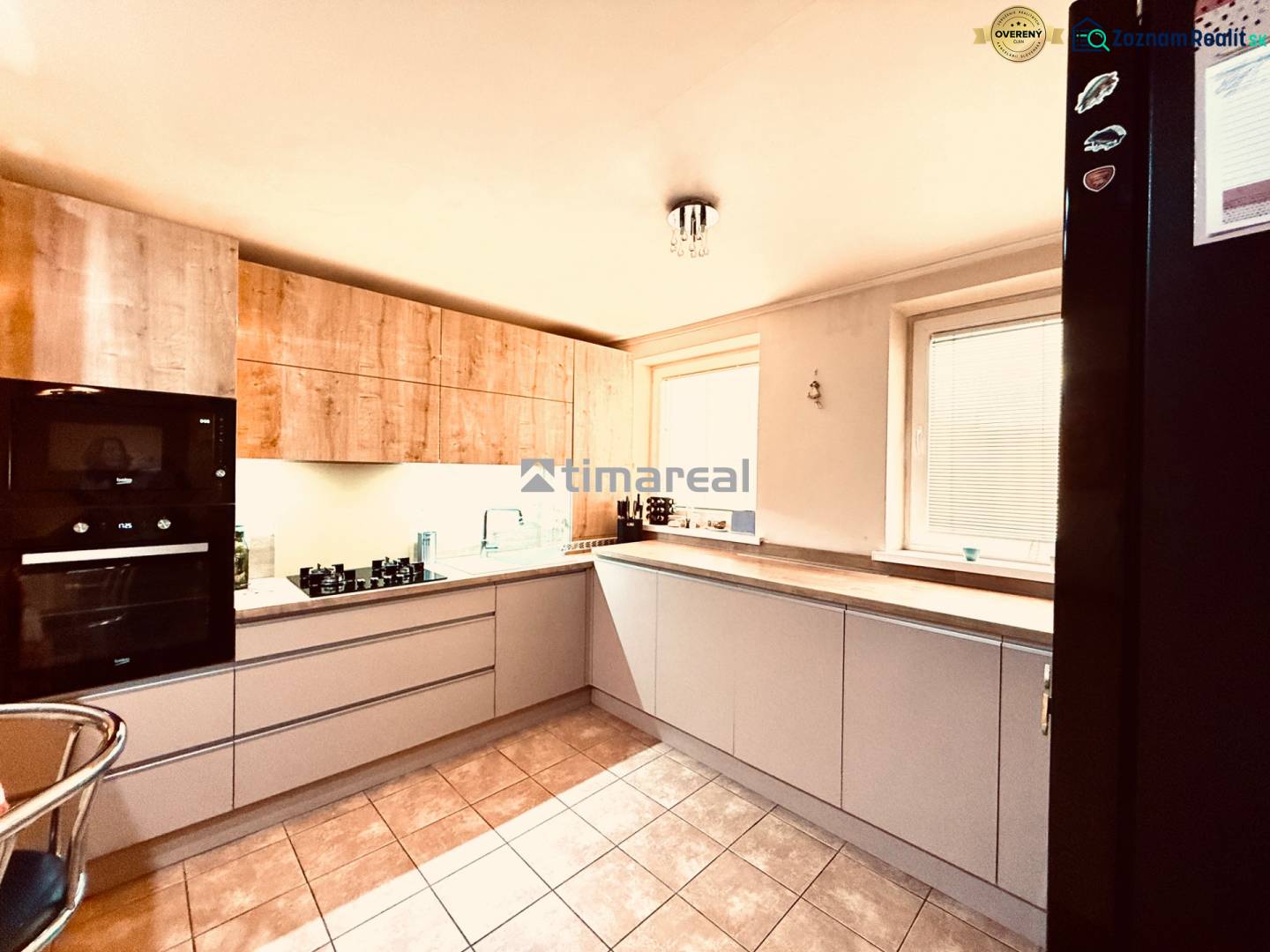 Konyha egy háromszobás lakásban csempével és fából készült dekorációval ellátott szekrényekkel.