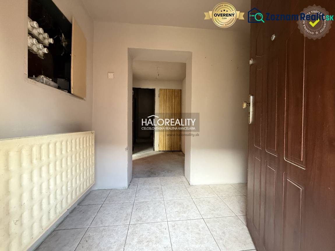 A családi ház előszobája fehér csempével és barna ajtókkal.