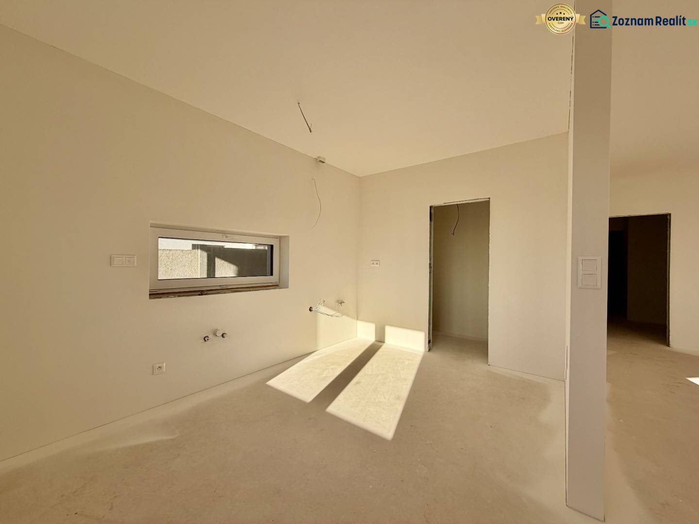 Tágas, nem berendezett szoba egy családi házban, ablakkal és ajtóval, padló nélkül.