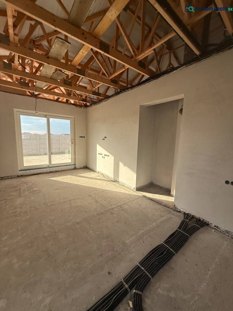 Családi ház belső tere látszó mennyezeti gerendákkal és elektromos szerelés előkészítésével.