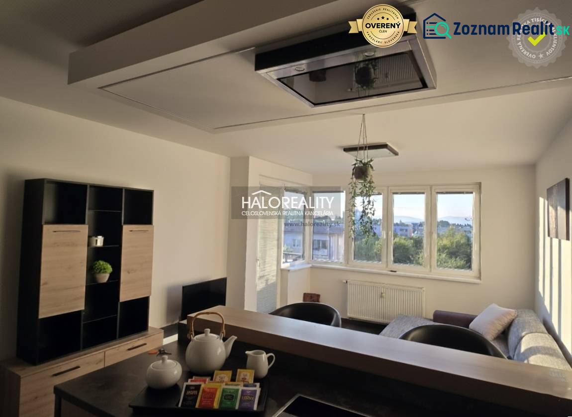 Nappali egy kétszobás lakásban világos falakkal és ablakokkal, bútorokkal berendezve.