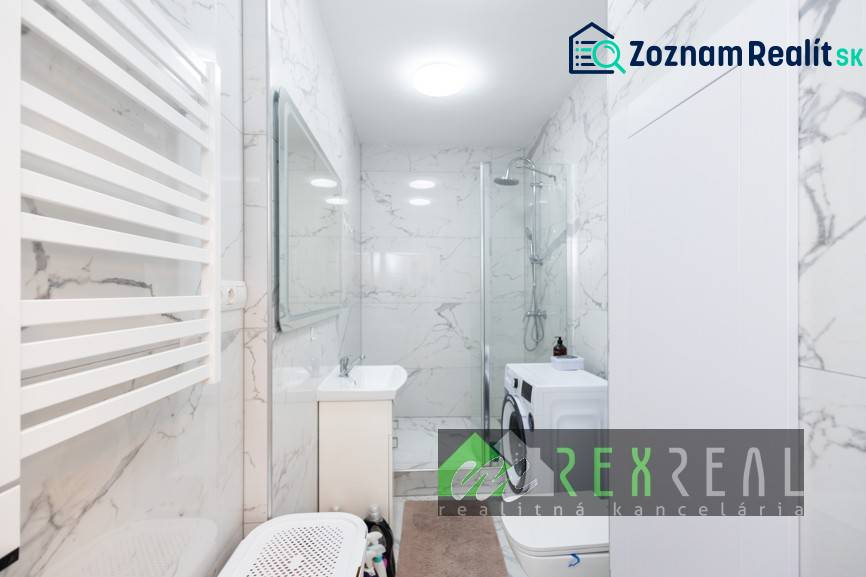 Fürdőszoba zuhanyzóval, mosógéppel és márványfallal egy háromszobás lakásban.