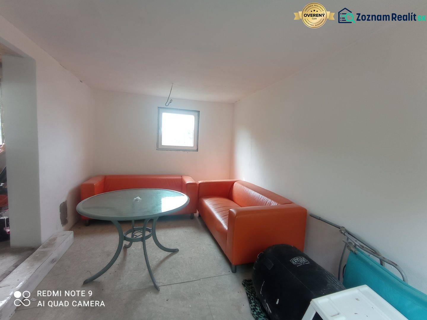 Narancssárga kanapék és kerek asztal egészítik ki a fehér falú ház belső terét.