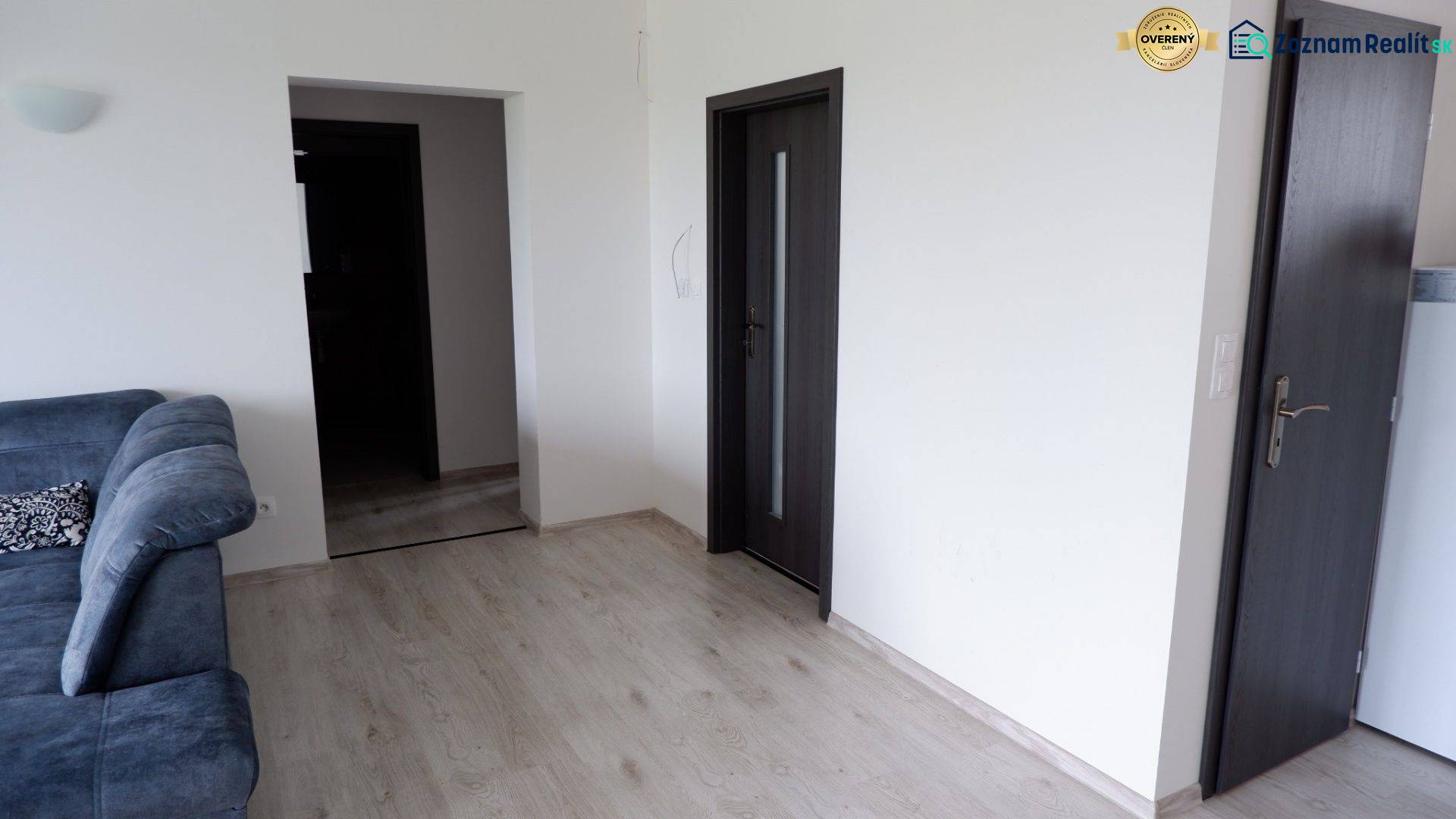 Családi ház belső tere kanapéval, fa dekorációjú padlóval és sötét ajtókkal.