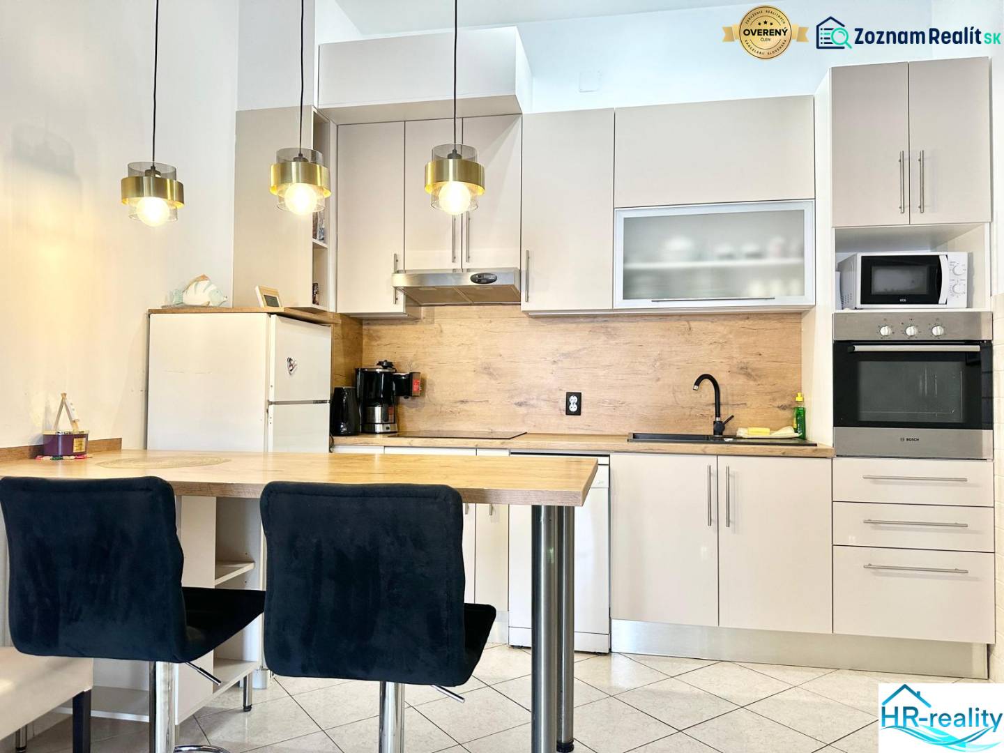 Konyha üdülő apartmanban bárpulttal, függő lámpákkal és fehér szekrénnyel.