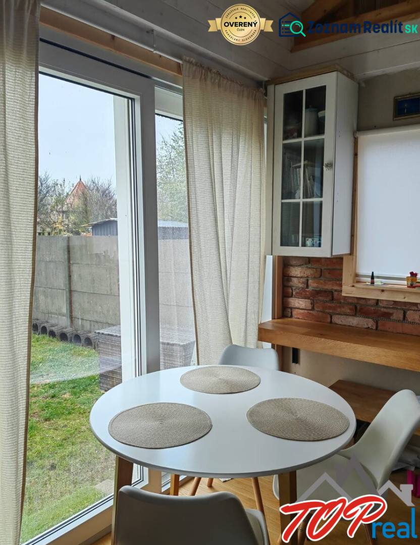 Étkező sarok egy családi házban, fa dekoros padlóval, téglafallal és nagy ablakokkal.