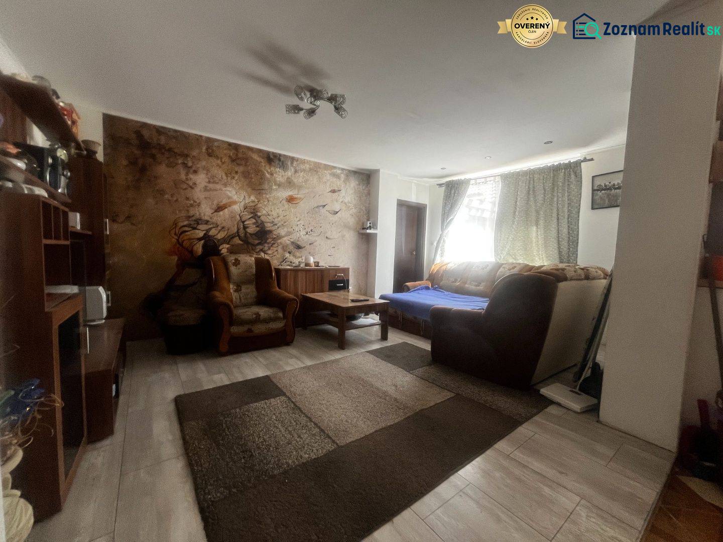 Nappali egy családi házban kanapéval, fotelekkel és falfestménnyel az ülőgarnitúra mögött.