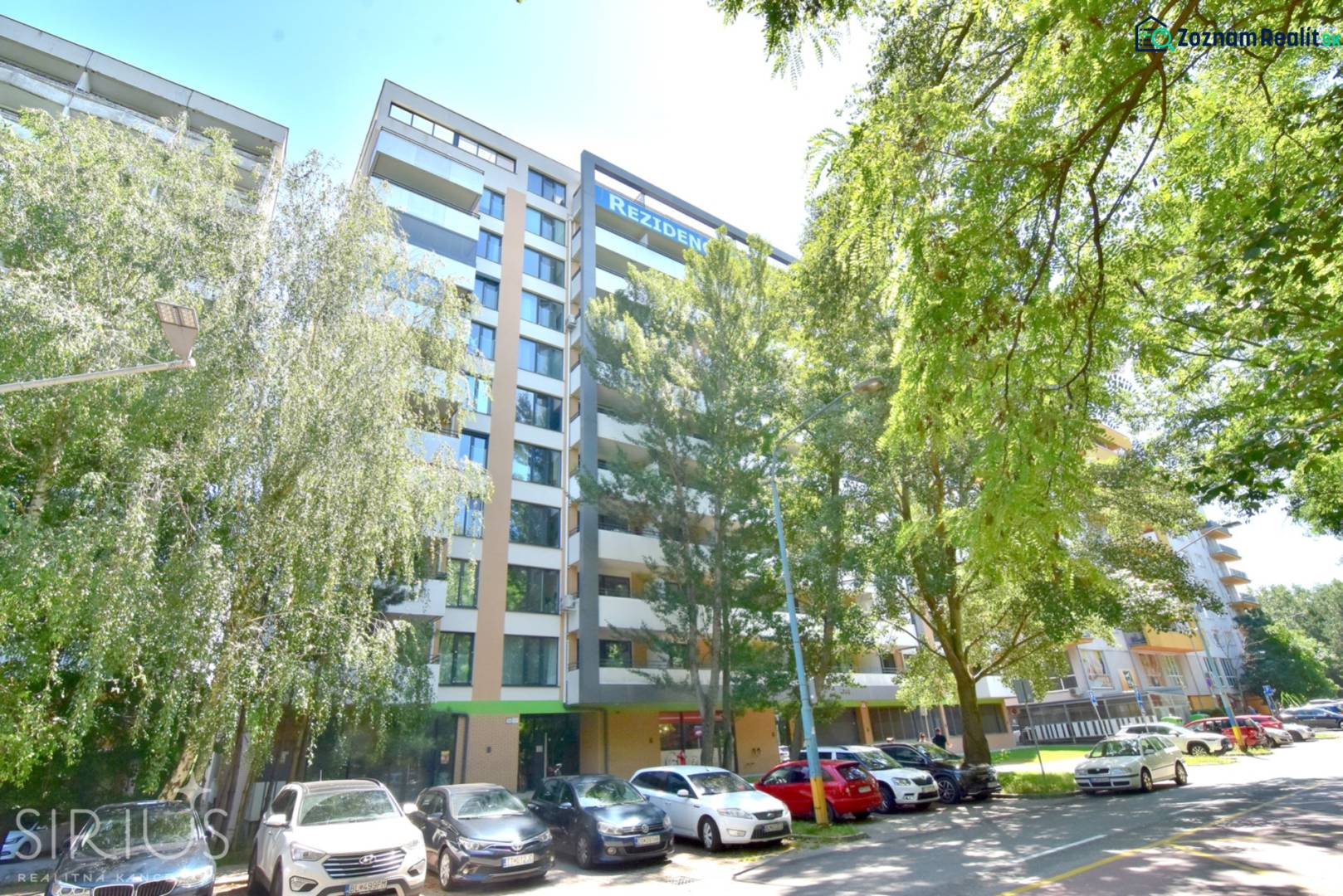 Egy lakóház az Antolska utcában, Pozsony-Petržalkán, zöldövezettel és parkoló autókkal körülvéve.